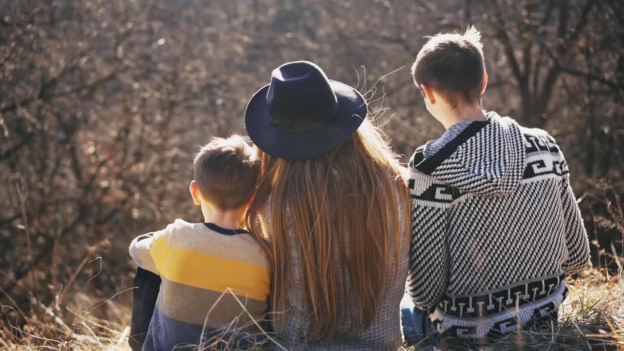 一个充满爱的家庭，一个母亲，一个父亲和一个儿子坐在大自然中拥抱视频素材