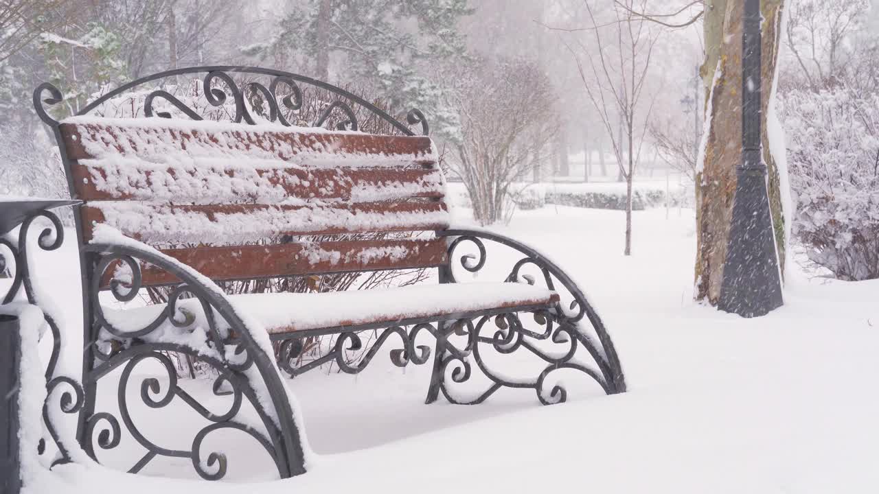 冬天的城市公园里，长椅上覆盖着雪和雪花视频素材