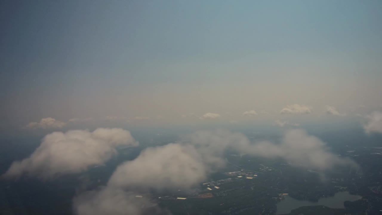 飞机在云上飞行，在美丽的绿草地上，土地上面是蓝色的天空视频素材