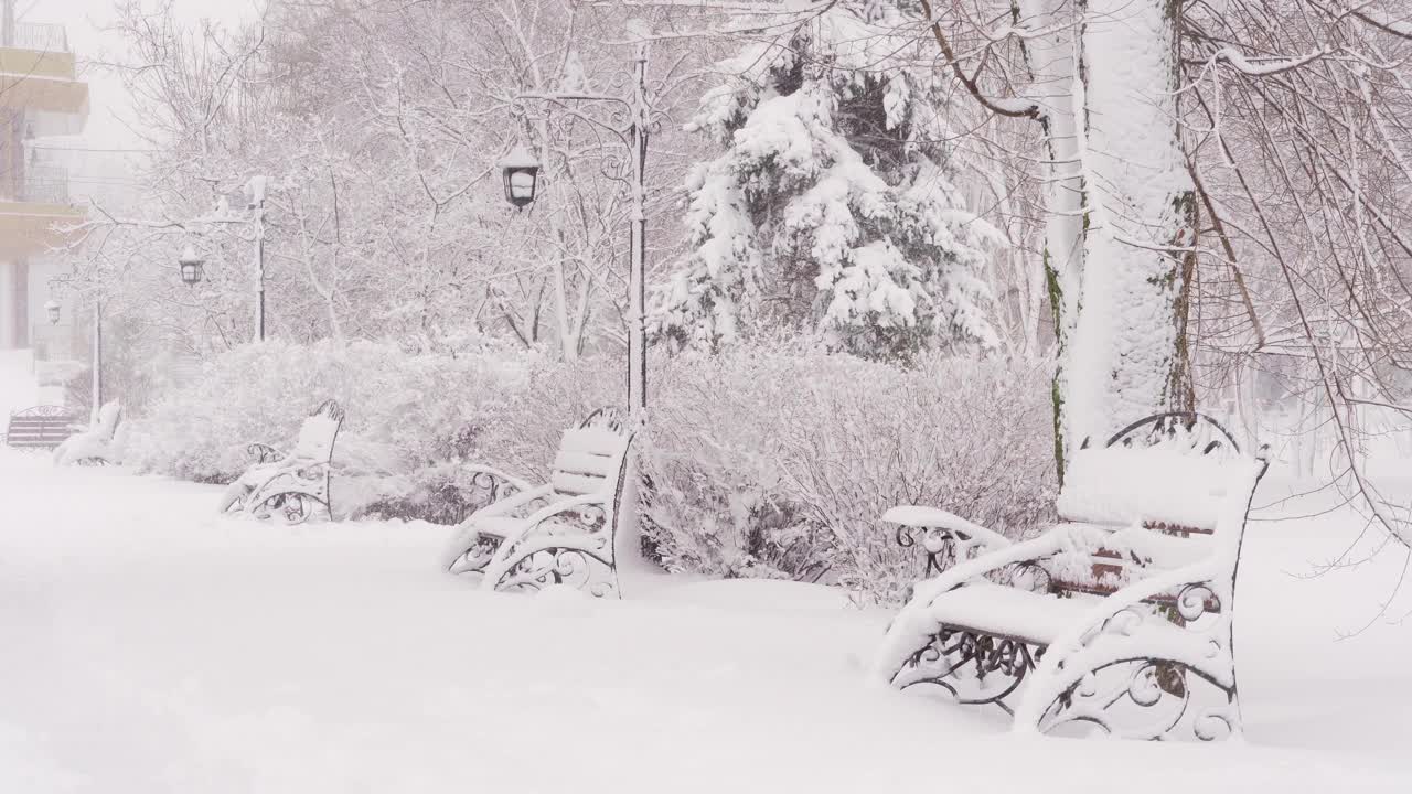 冬天的城市公园里，长椅上覆盖着雪和雪花视频素材