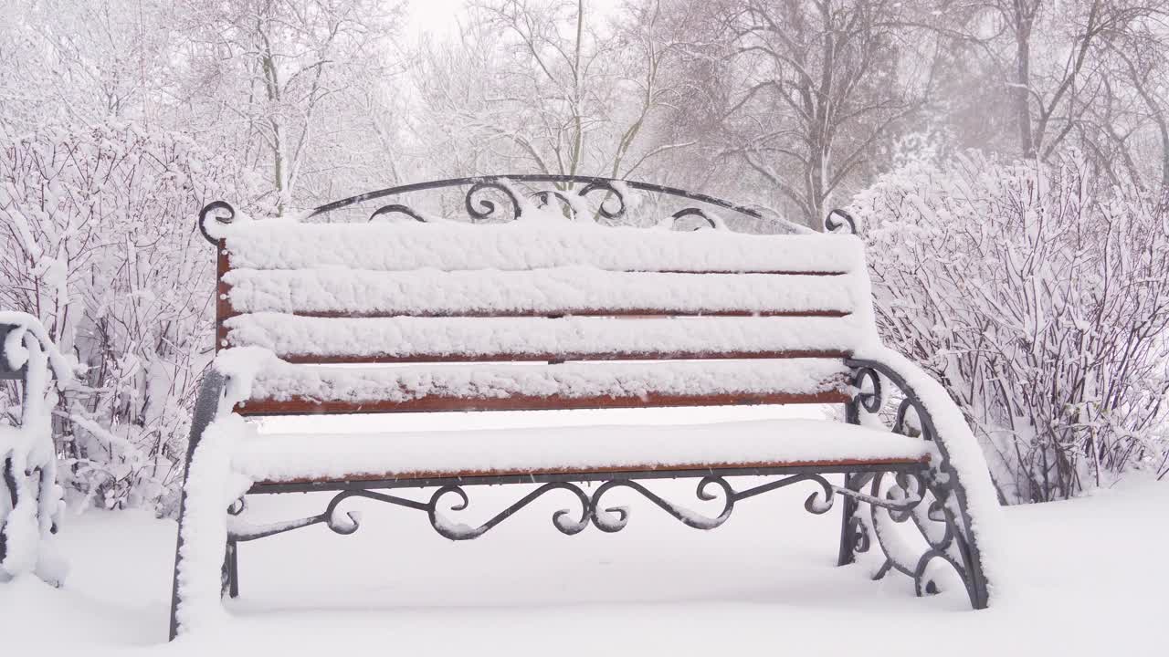 冬天的城市公园里，长椅上覆盖着雪和雪花视频素材