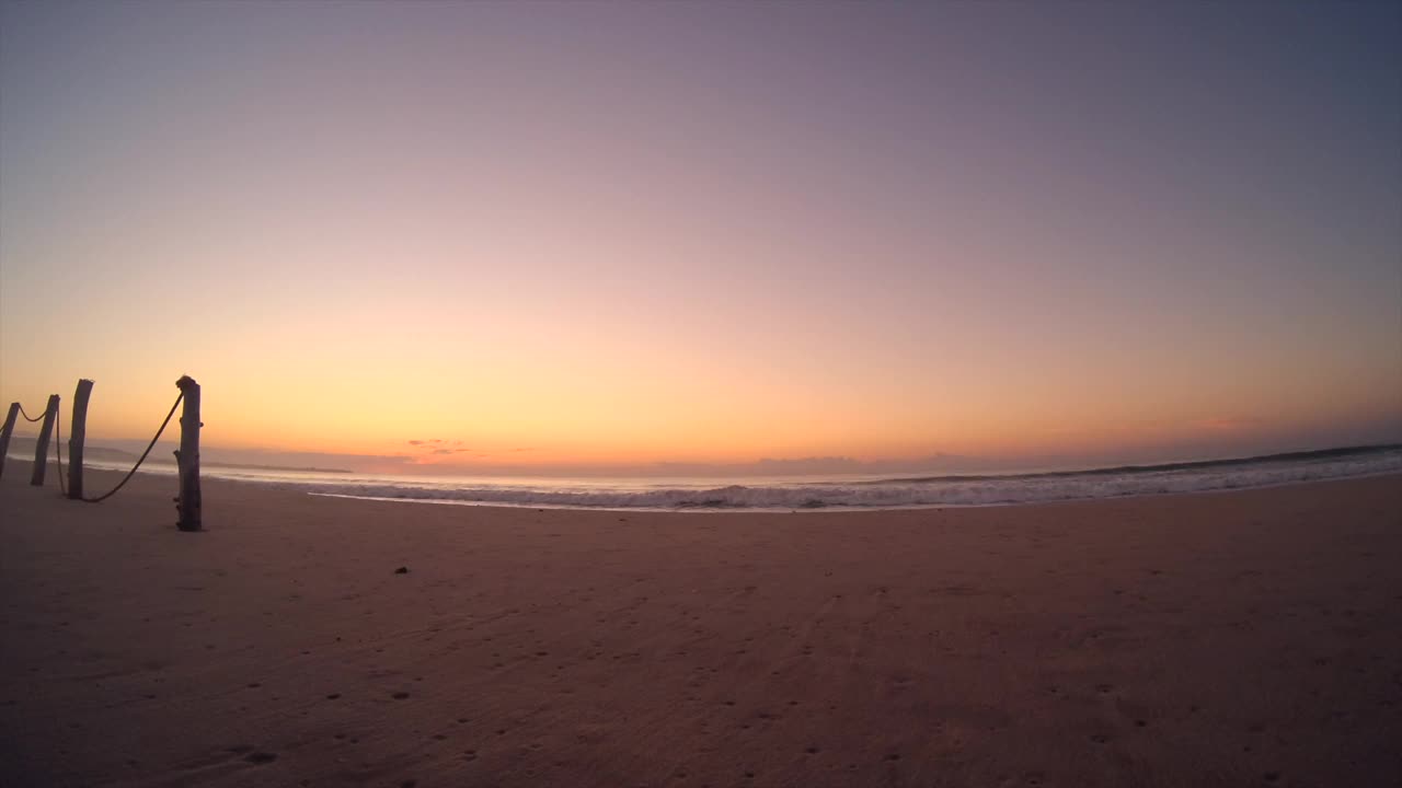 日出海滩。海岸上黎明的时间流逝。太阳在海滩上升起。快速拍摄阳光和波浪。视频素材