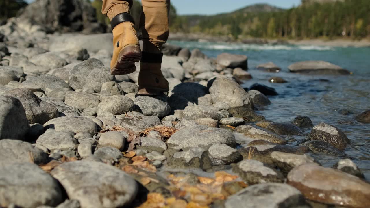 脚的近距离的靴子登山者男性远足者旅行者男人走和跳在岩石附近的山河流视频素材