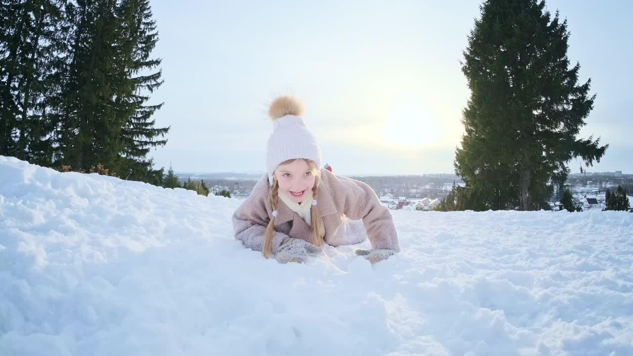 女孩喜欢冬天。快乐可爱的女孩躺在公园的雪地上视频素材