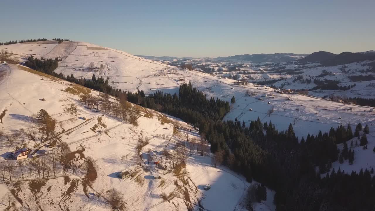 鸟瞰图上的小村庄，在冬天被雪覆盖的山丘上散落着房屋，裸露的喀尔巴阡山脉在乌克兰。视频素材