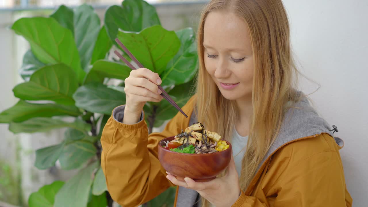 一个年轻的女人在一个提供poke碗的漂亮的咖啡馆里享受她的晚餐。快速和健康。时尚的食品的概念视频素材