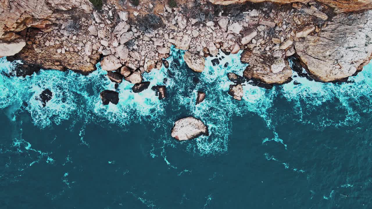 鸟瞰图的海浪打破在蓝色的海洋岩石。视频素材