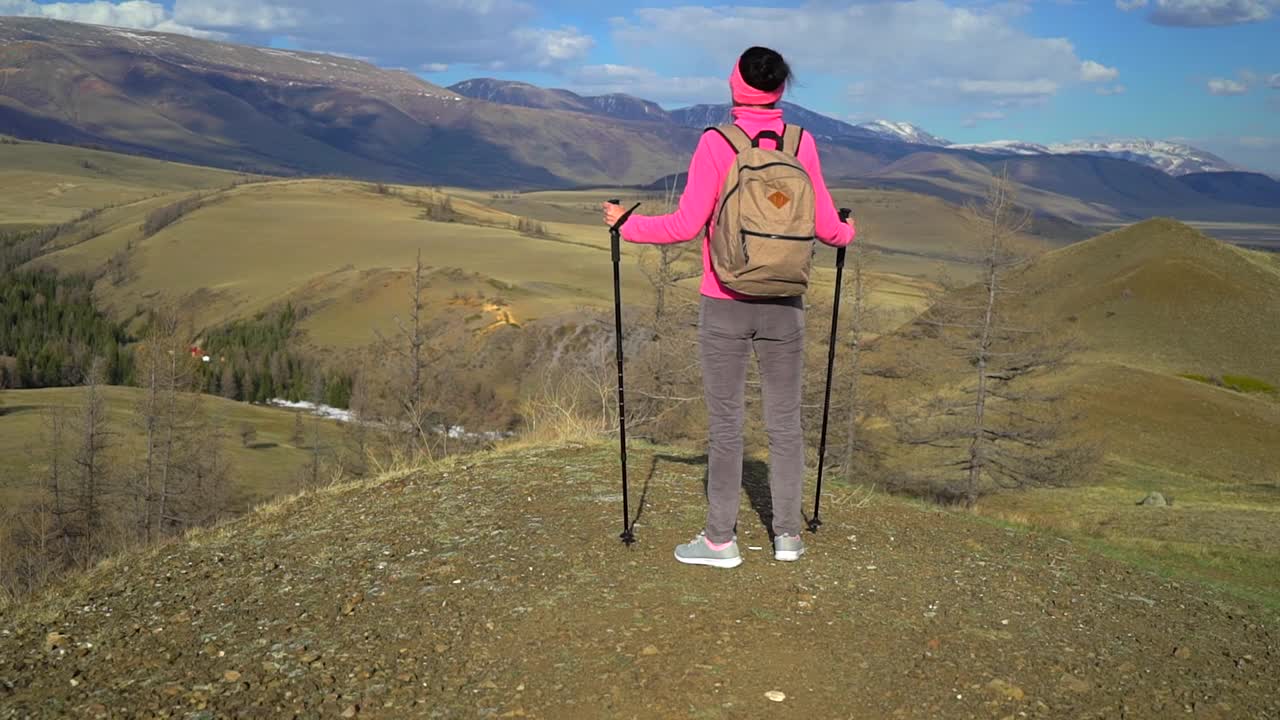 旅行家女子背包和徒步杆享受山顶视频素材