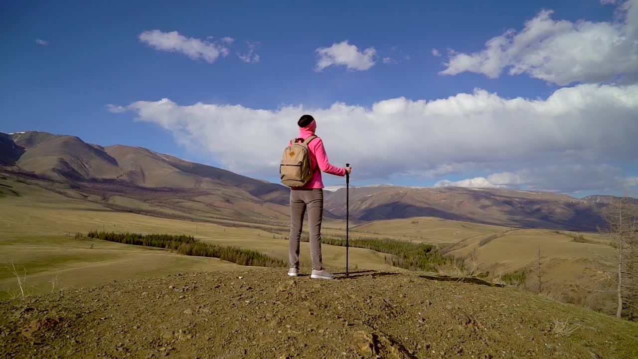 旅行家女子背包和徒步杆享受山顶视频素材