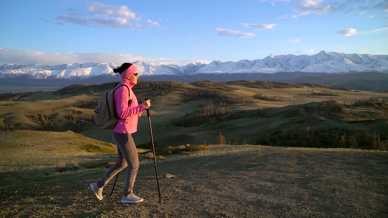 徒步旅行的女游客背着背包，拄着拐杖徒步爬上山顶视频素材