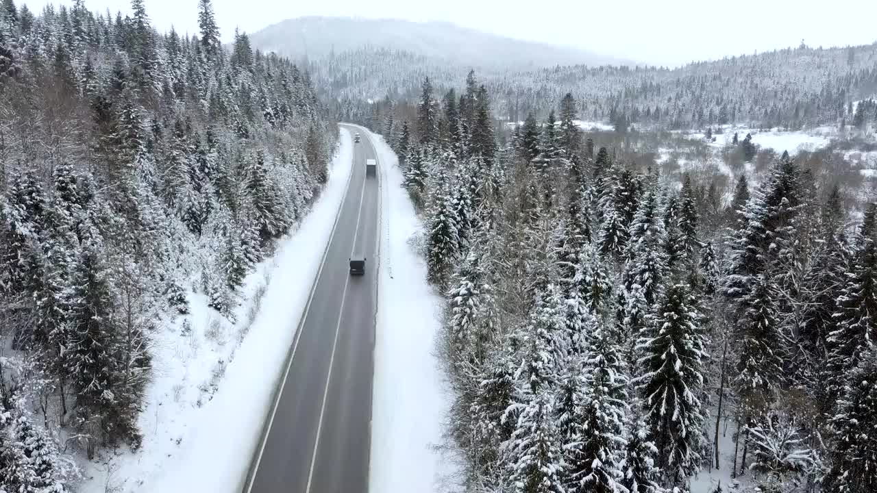 穿过森林的山间公路。山顶有雾，冬天自然下雪。一架无人机在山边的俯视图视频素材