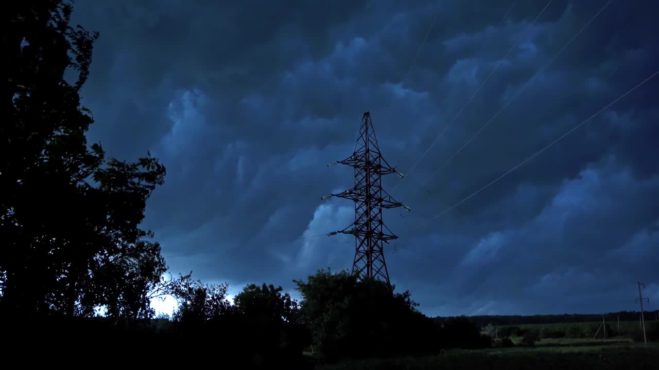 自然界中有暴风雨天气。乌云在高压电塔上空移动。傍晚强风摇动着树木。视频素材