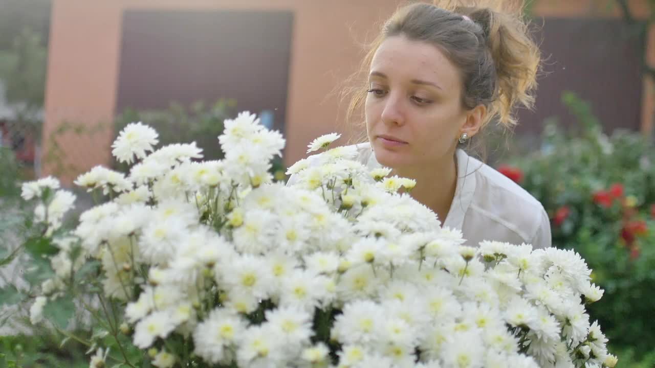 漂亮的小女孩正站在公园里的一丛白菊花旁，在春天的时候，有过敏、哮喘或过敏的概念视频素材