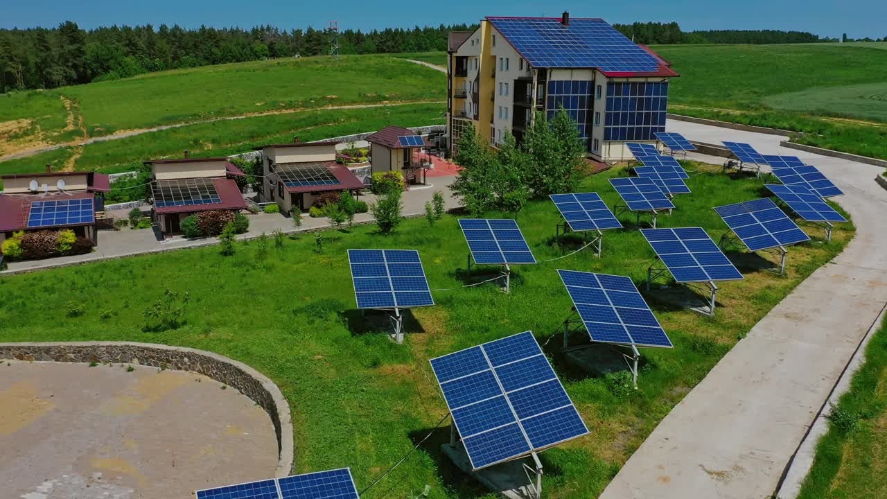 草地上的太阳能电池板。现代建筑与自然之间，屋顶和侧壁上有创新的蓝色太阳能电池。替代绿色能源生产。鸟瞰图。视频素材