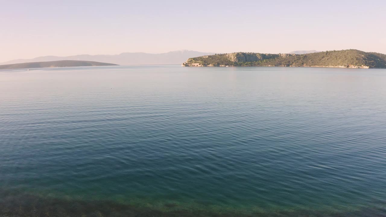 日出时，航拍镜头靠近平静的海水飞行视频素材