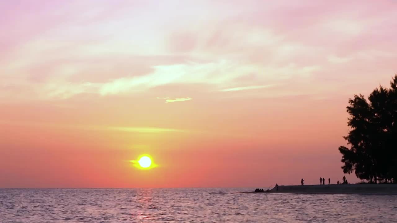 海上的红色日落。黄色的太阳触及水面，粉红色的色调天空在一个夏天的傍晚。太平洋海滩的日落。太阳在旋转的云奇妙的自然日落背景视频素材