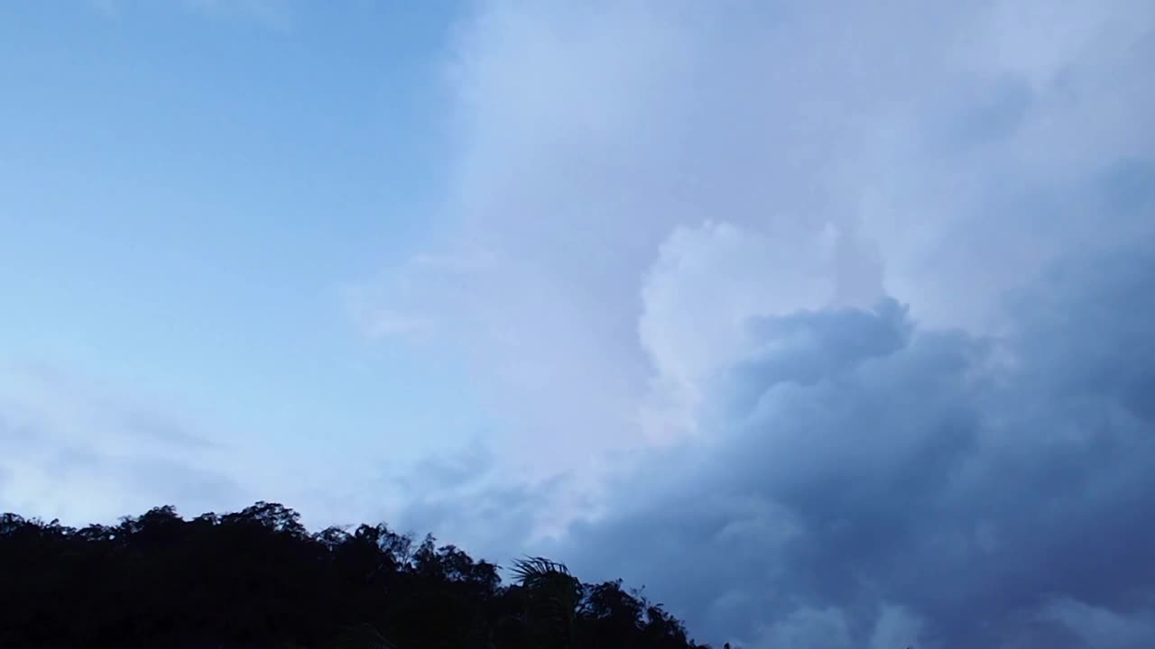 在热带雨季，黄昏天空中的乌云在山上缓慢移动。在黑暗的夜晚，戏剧性的灰色，蓬松的积云危险的云在天空中移动。Cloudscape背景。视频素材