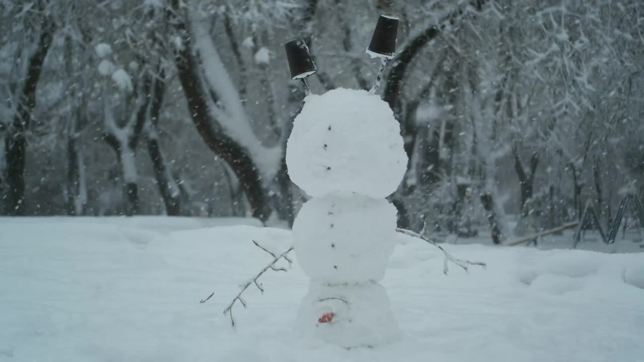 快乐滑稽的雪人杂技演员倒立在头上，背景是一场强降雪。视频素材