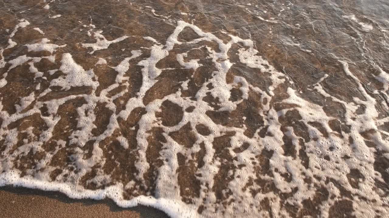 航拍的金色海滩遇见深蓝色的海水和泡沫的波浪视频素材