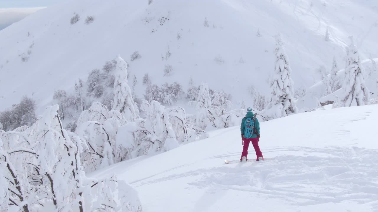 航拍:在年轻的滑雪者周围飞行，在她下降前观察风景视频下载