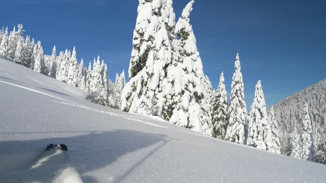 近距离观察:一个面目全非的男人在劈板旅行中踏着新鲜的粉末雪。视频素材