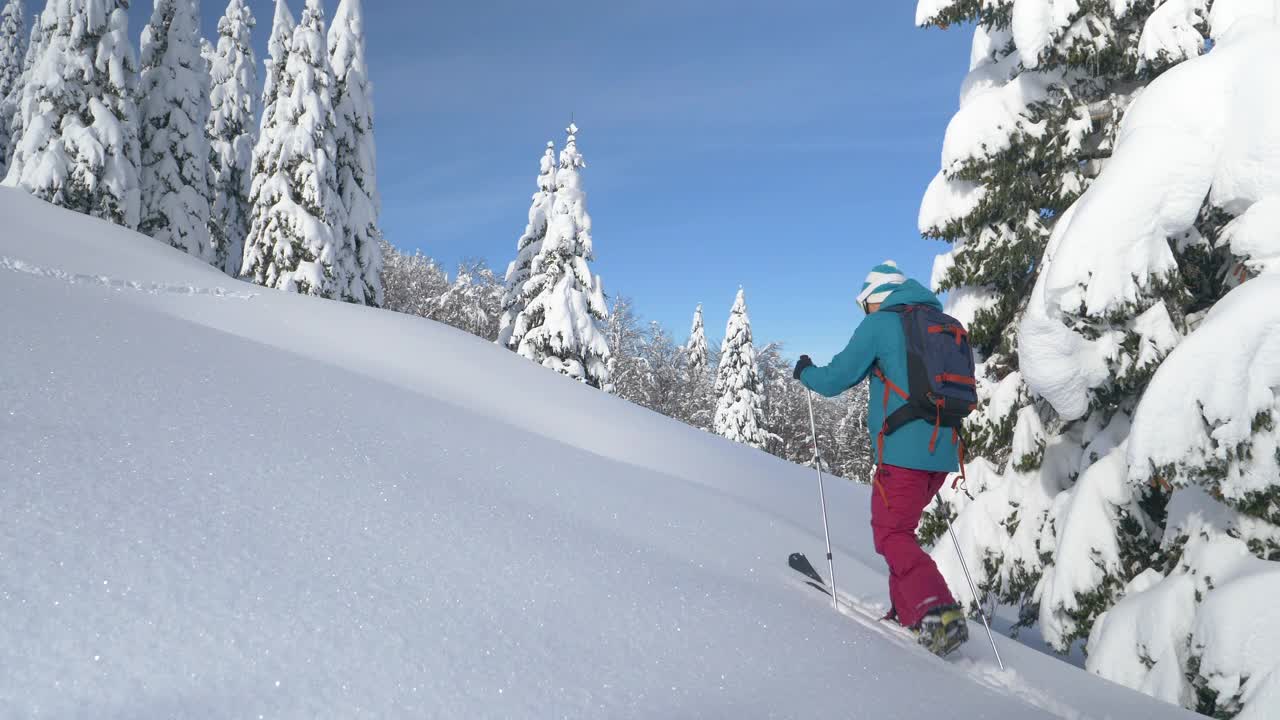 在滑雪旅行中，一名女子在爬山时踩着厚厚的积雪视频素材