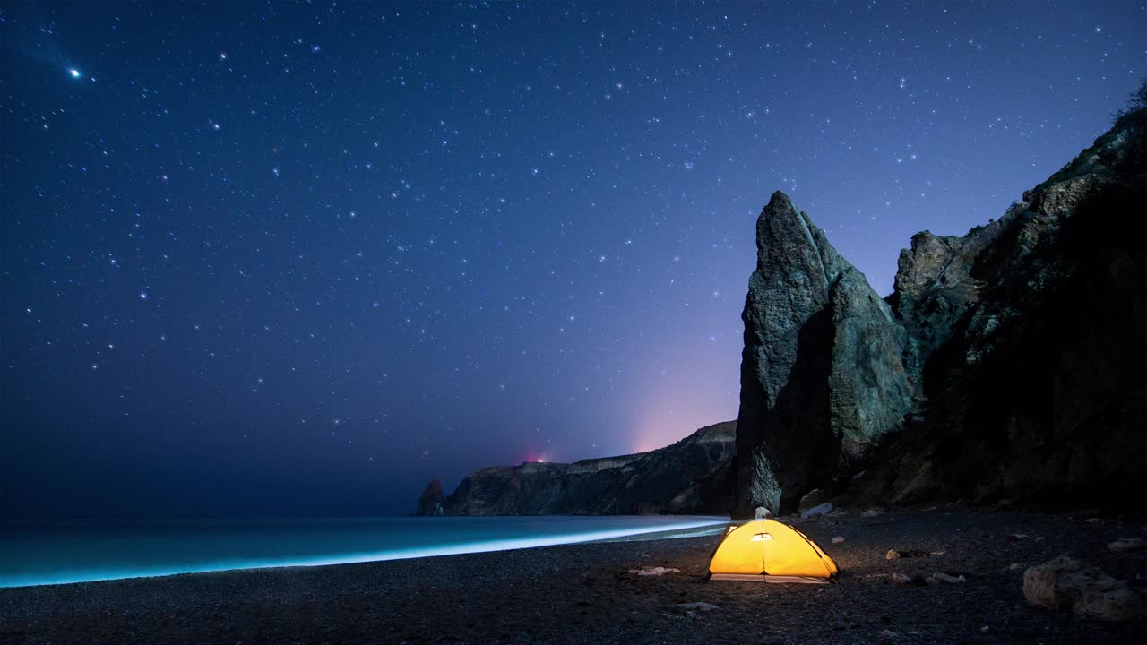 在闪烁的星空下，海边的发光帐篷和岩石。Cinemagraph。视频素材