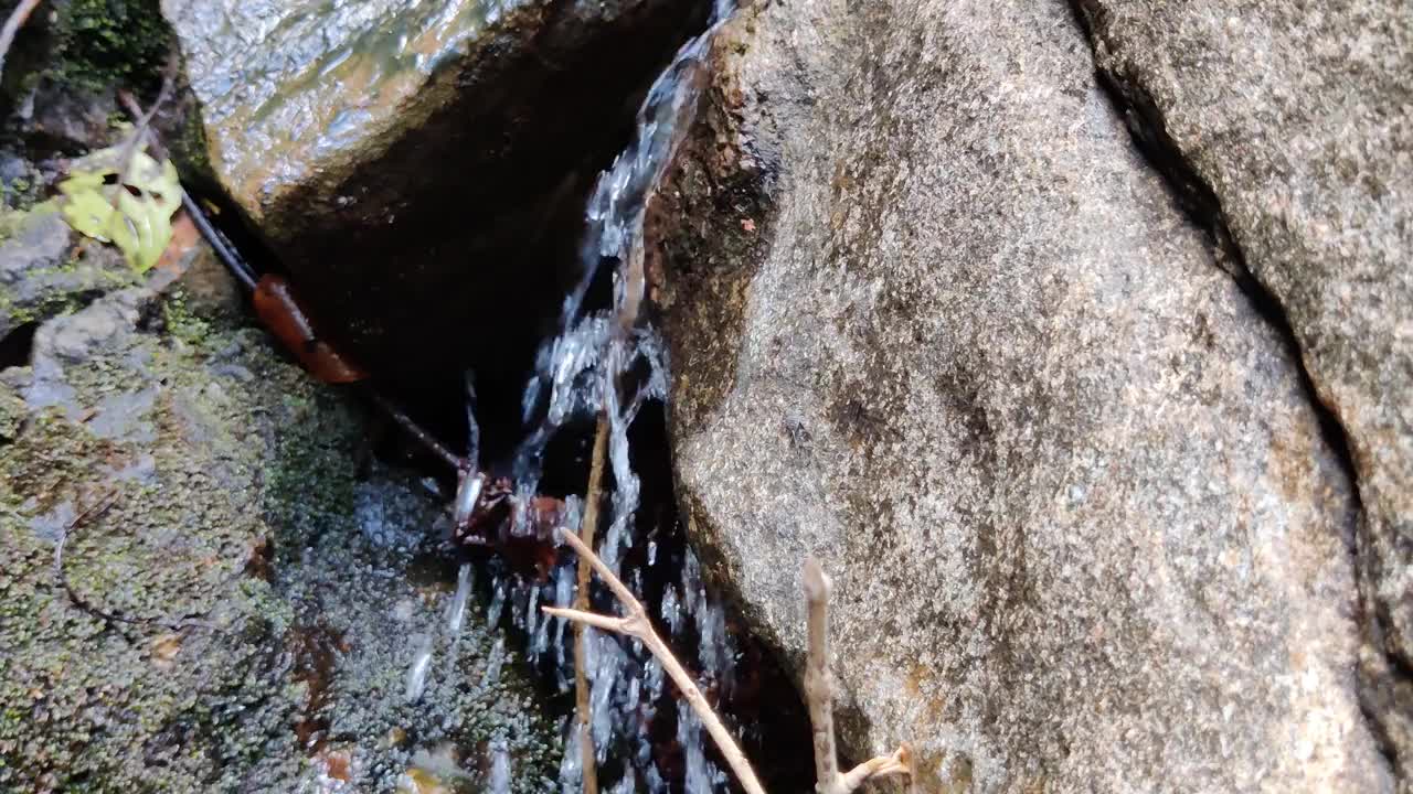 流动的水滴之间的坚硬的岩石特写视频素材