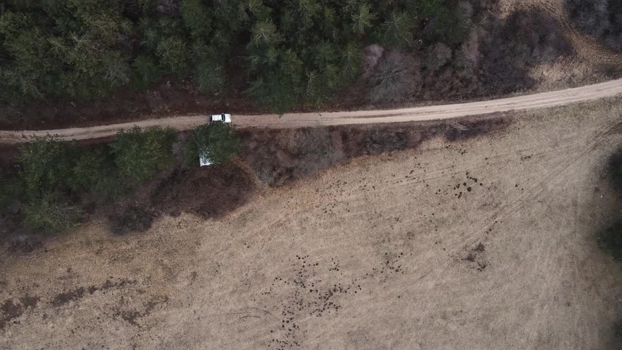 鸟瞰图的汽车行驶在碎石公路通过森林视频素材