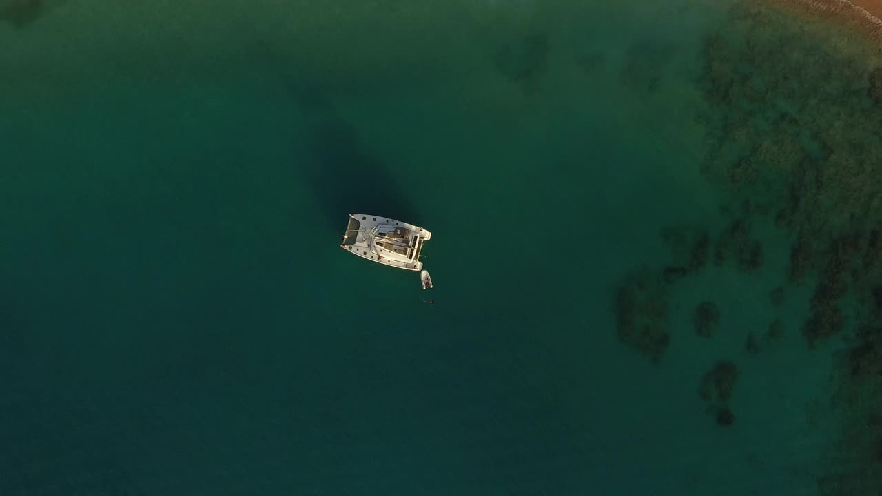 高空无人机拍摄的日落时分热带海滩上的一艘双体船。视频素材