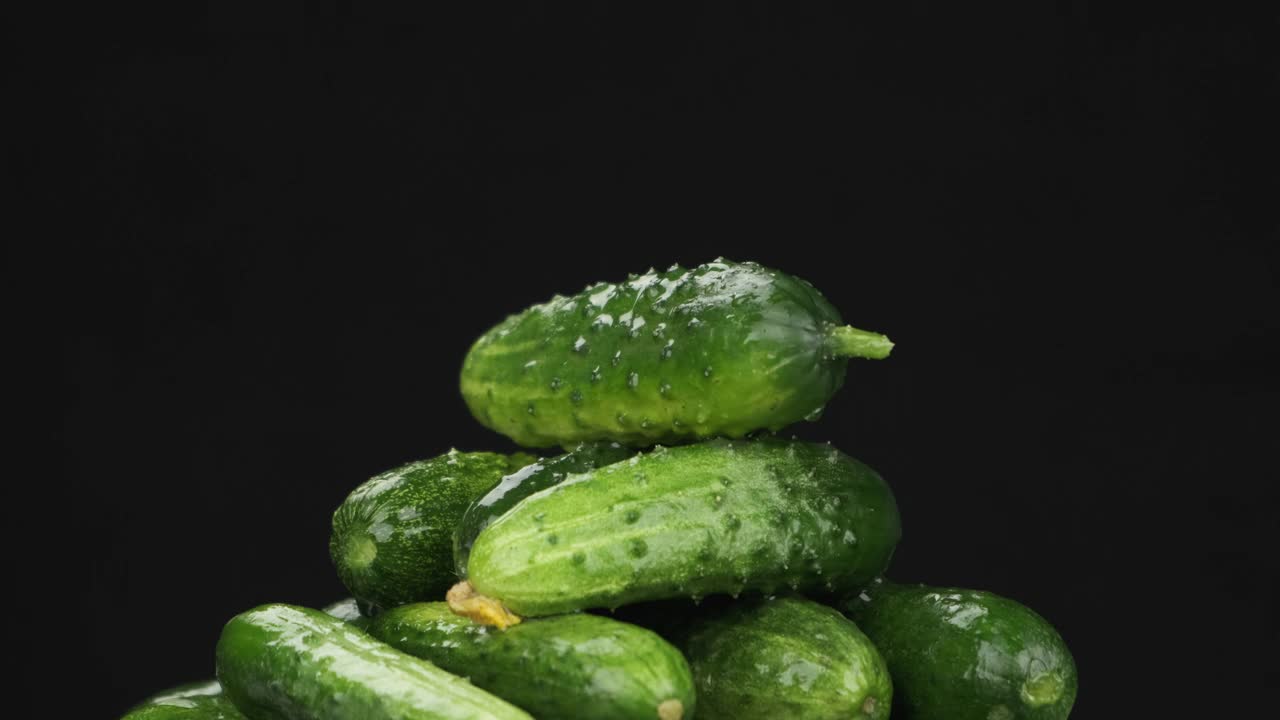 雨滴落在一堆旋转的绿黄瓜上。视频素材