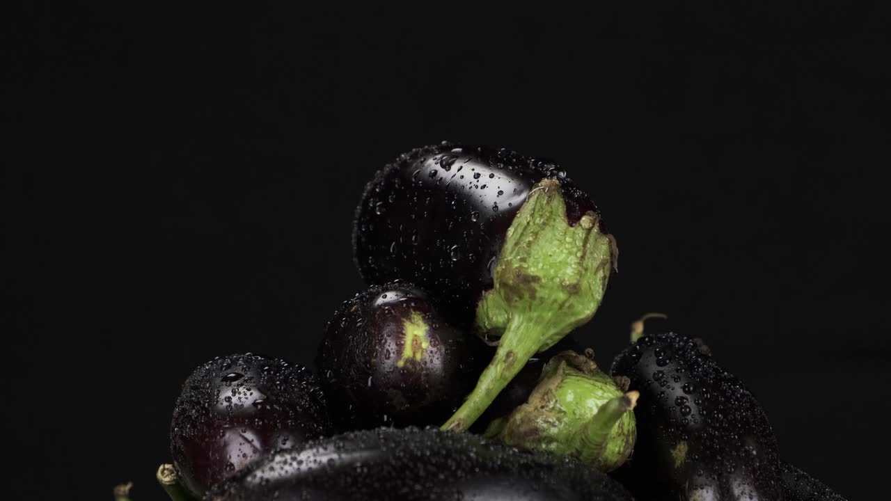 雨滴落在一堆旋转的紫色茄子上。视频素材