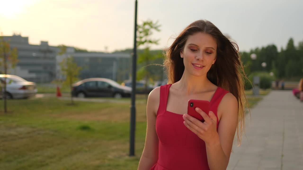 漂亮漂亮的年轻购物女孩女人在红色的裙子与包包裹走在户外街道城市说话手机智能手机视频素材