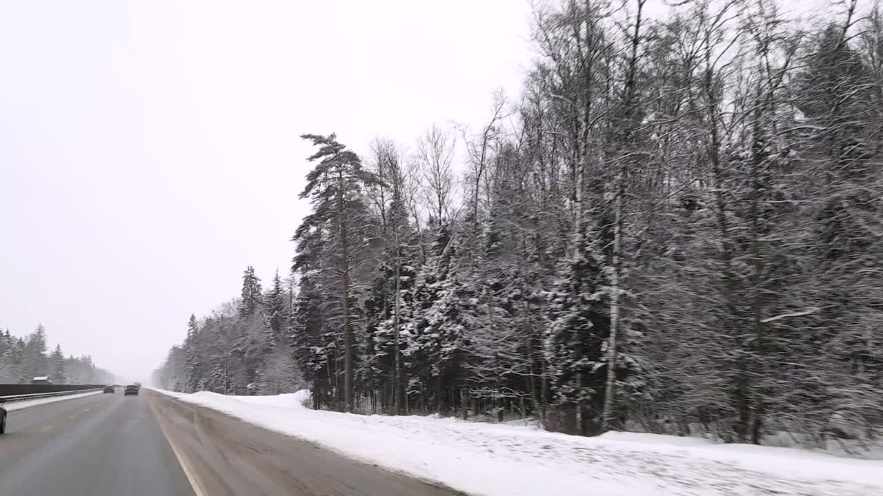 俄罗斯。冬天下雪的雅罗斯拉夫尔高速公路上，透过挡风玻璃观看汽车视频素材