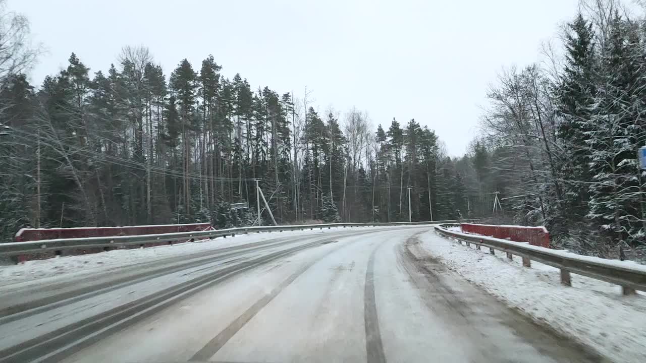 透过挡风玻璃，一辆汽车在森林中湿滑的道路上转弯视频素材