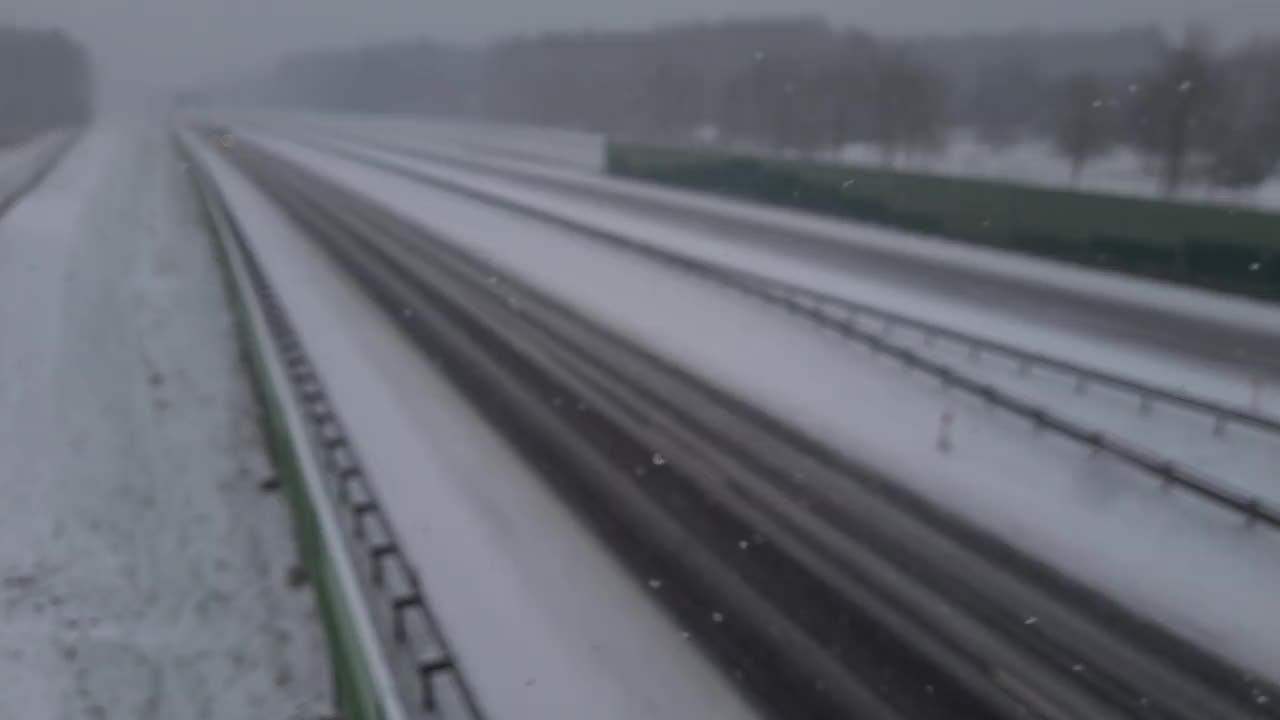 从桥上俯瞰，在暴风雪中高速公路上行驶的汽车视频下载