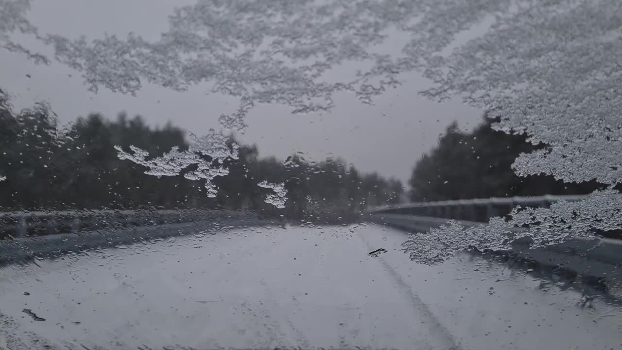 从机舱内看冬天，汽车刮水器会清理挡风玻璃上的积雪。危险的天气状况，道路安全。视频素材