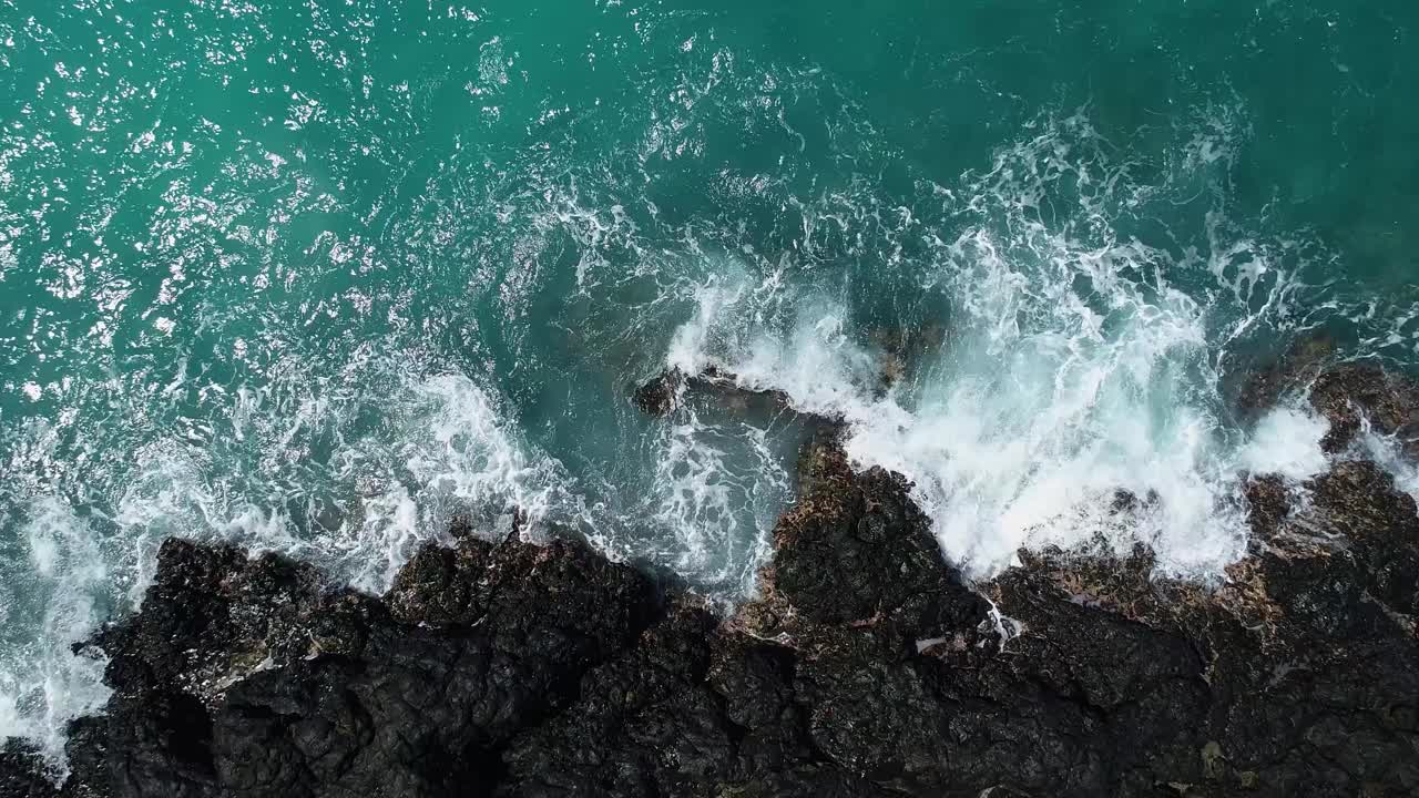 海浪在岩石海滩上破碎的鸟瞰图视频素材