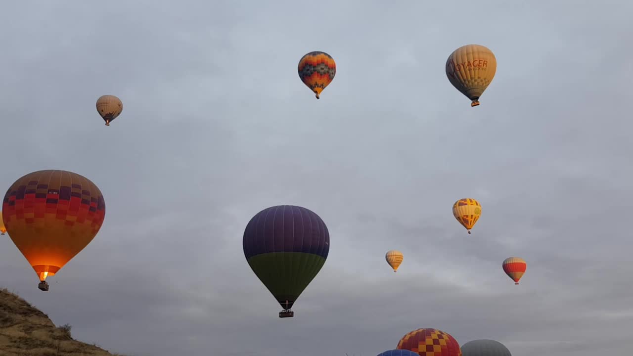 彩色的热气球上升并漂浮在土耳其卡帕多西亚山区的天空中视频素材