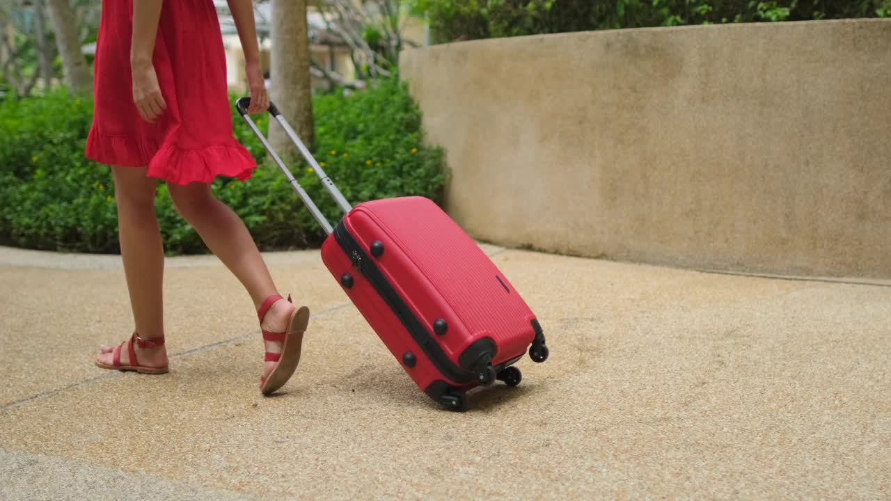 美丽的旅行者女人女孩在豪华度假村走在红色的衣服手提箱视频素材