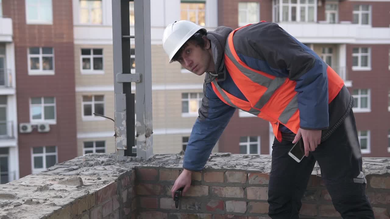 建筑工人在高层建筑的施工现场用激光卷尺进行测量。视频素材