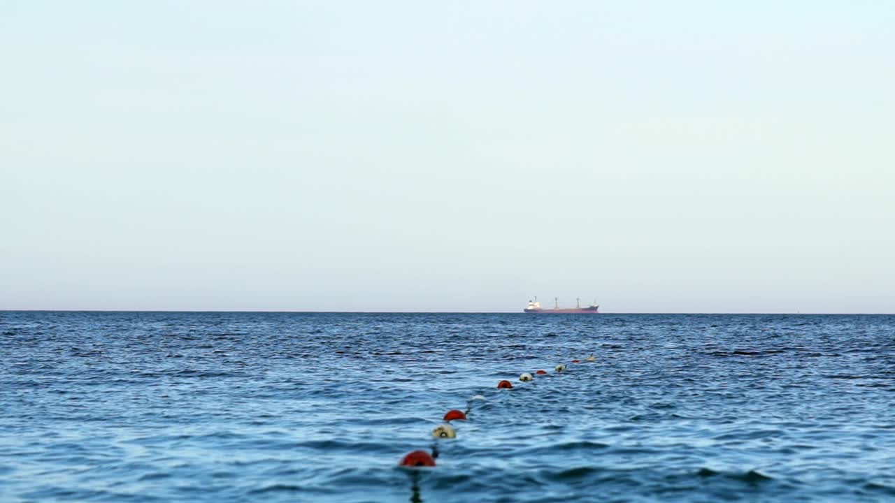 蓝色的海水。保留海上浮标标明的游泳区域。轮船在远处的水面上航行。视频素材