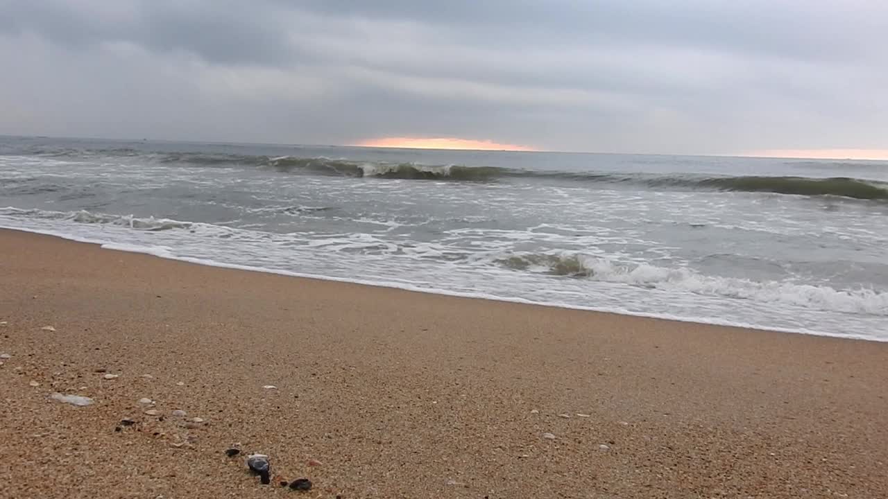 在景观中，太阳在海洋附近升起。特写镜头日出海滩。多云的海滩和巨浪袭击海岸。多云的海洋和平静的海滩景观。惊人的平静的海滩。早晨乌云密布的海滩上乌云密布。海面上的小波浪日落。金色的太阳视频素材