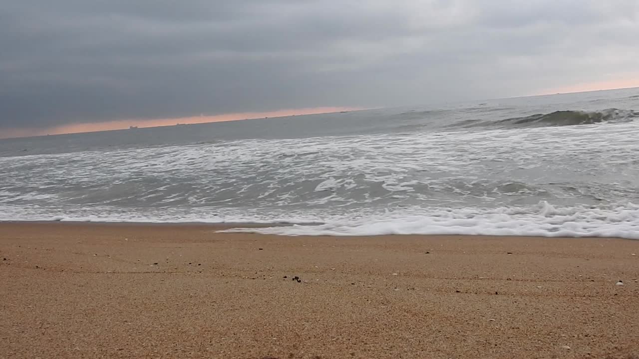 多云的海滩和巨浪袭击海岸。多云的海洋和平静的海滩景观。惊人的平静的海滩。早晨乌云密布的海滩上乌云密布。海面上的小波浪日落。金色的夕阳和黄色的阳光。视频素材