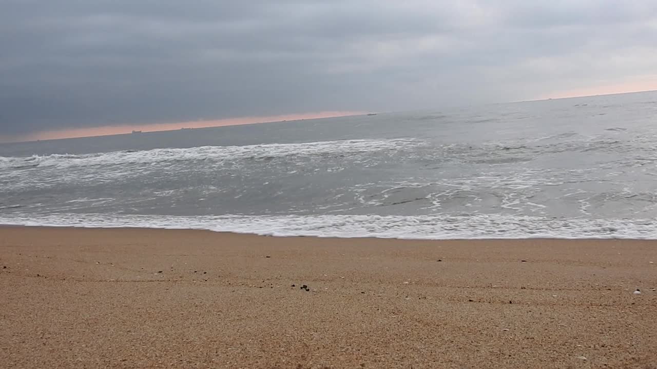 多云的海滩和巨浪袭击海岸。多云的海洋和平静的海滩景观。惊人的平静的海滩。早晨乌云密布的海滩上乌云密布。海面上的小波浪日落。金色的夕阳和黄色的阳光。视频素材