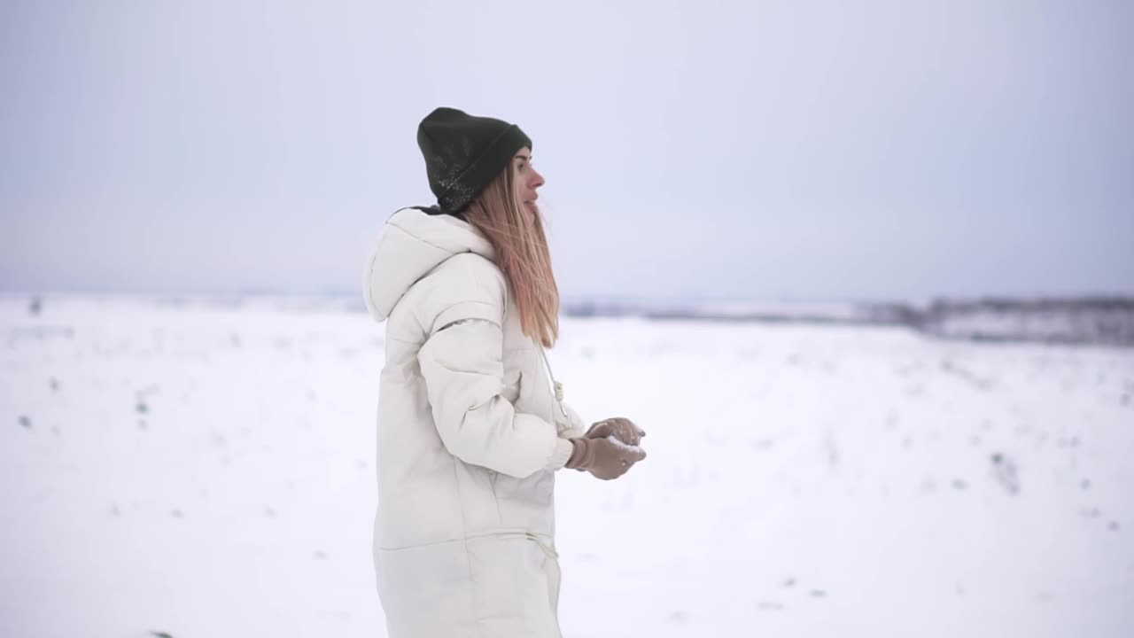 顽皮的年轻女子在户外享受第一场雪，把雪球扔到朋友的背上视频素材