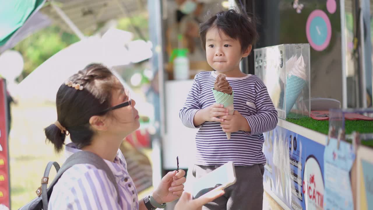 亚洲小男孩和妈妈在冰淇淋餐车吃冰淇淋视频素材