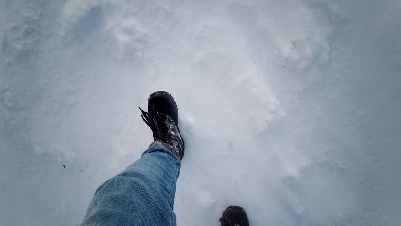 冬季散步波夫徒步旅行场景与腿在高雪。在深雪中向下看脚，第一人称视角。视频素材