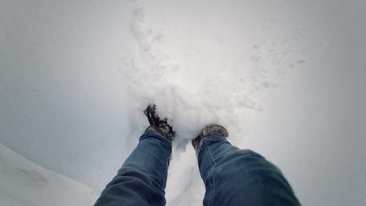 冬季散步波夫徒步旅行场景与腿在高雪。在深雪中向下看脚，第一人称视角。视频素材