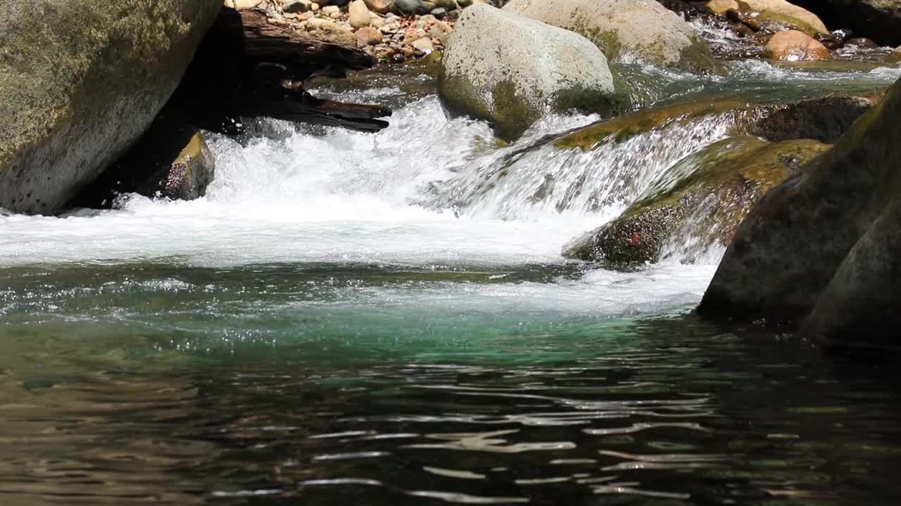 有泡沫的水流过河上的大岩石视频下载